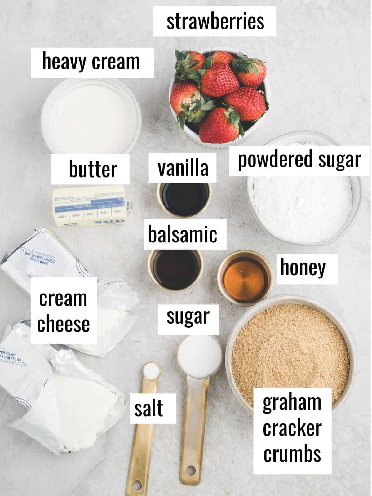 Ingredients for a dessert recipe, including strawberries, heavy cream, butter, vanilla, powdered sugar, cream cheese, balsamic, honey, sugar, salt, and graham cracker crumbs, each labeled on the image.
